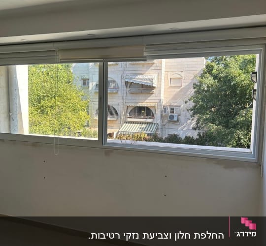 חלון אלומיניום עם מסגרת כסופה וקיר לבן